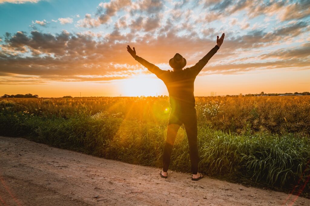 Retiring overseas-A man standing with arms raised toward the sunset