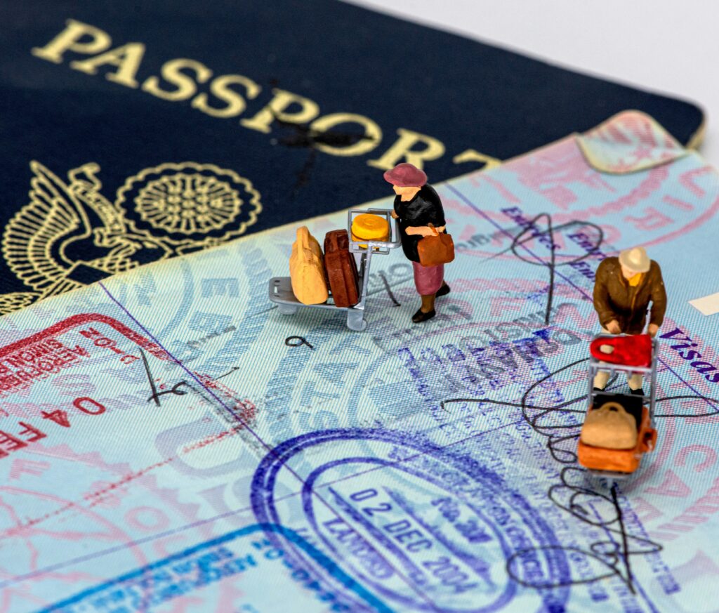 Small plastic figures pushing luggage carts across an open passport