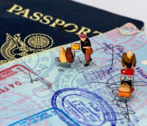 Small plastic figures pushing luggage carts across an open passport