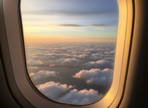 part time life overseas-view from an airplane window flying above clouds at sunset